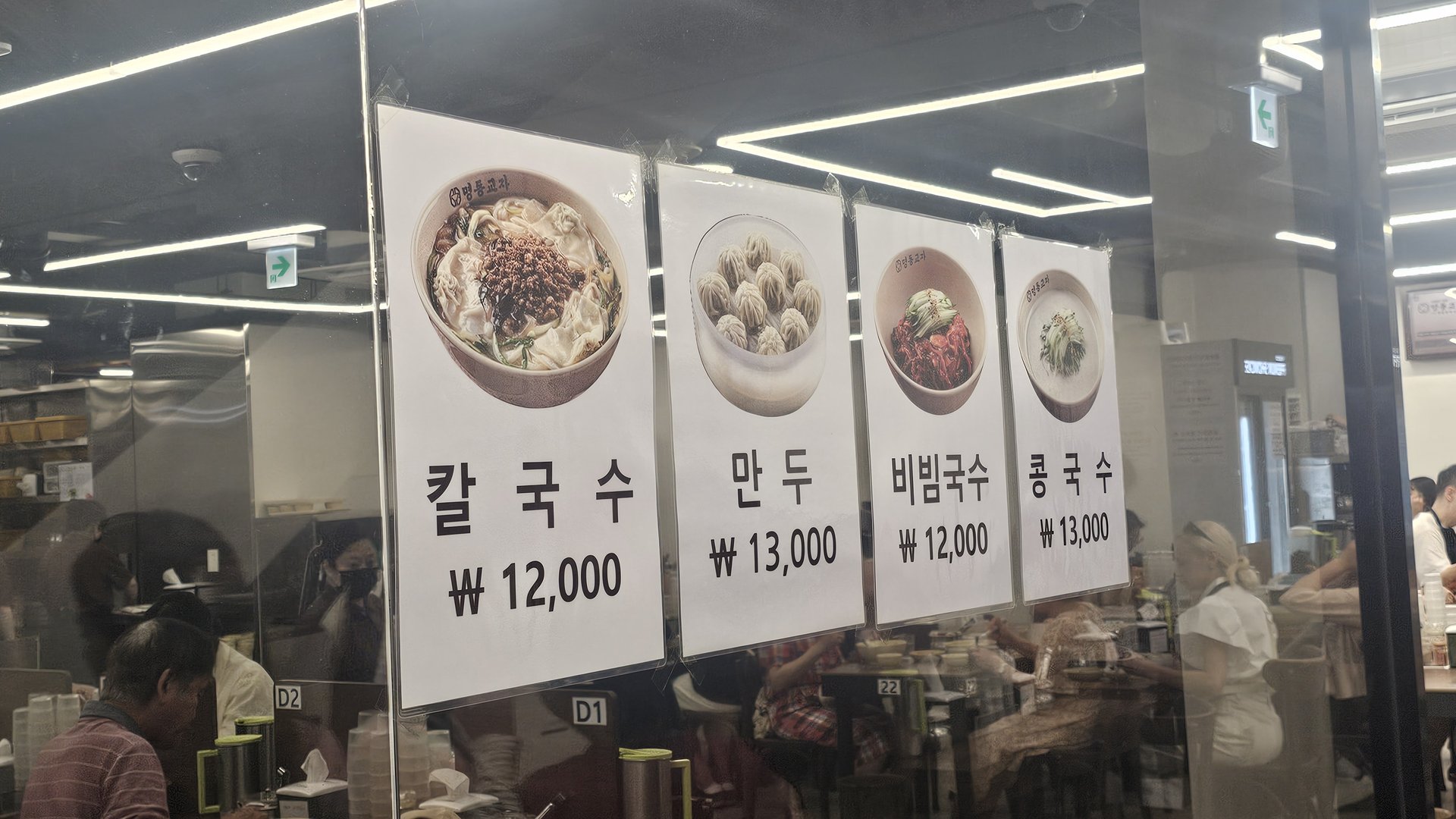 Menu board closeup at Myeongdong Gyoja showing kalguksu 12000 won and mandu 13000 won