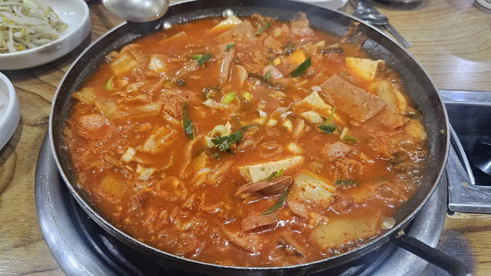 汝矣島サムォンジョンで鍋の中でぐつぐつ煮えるプデチゲ。スパム、豆腐、キムチ、ネギ入り