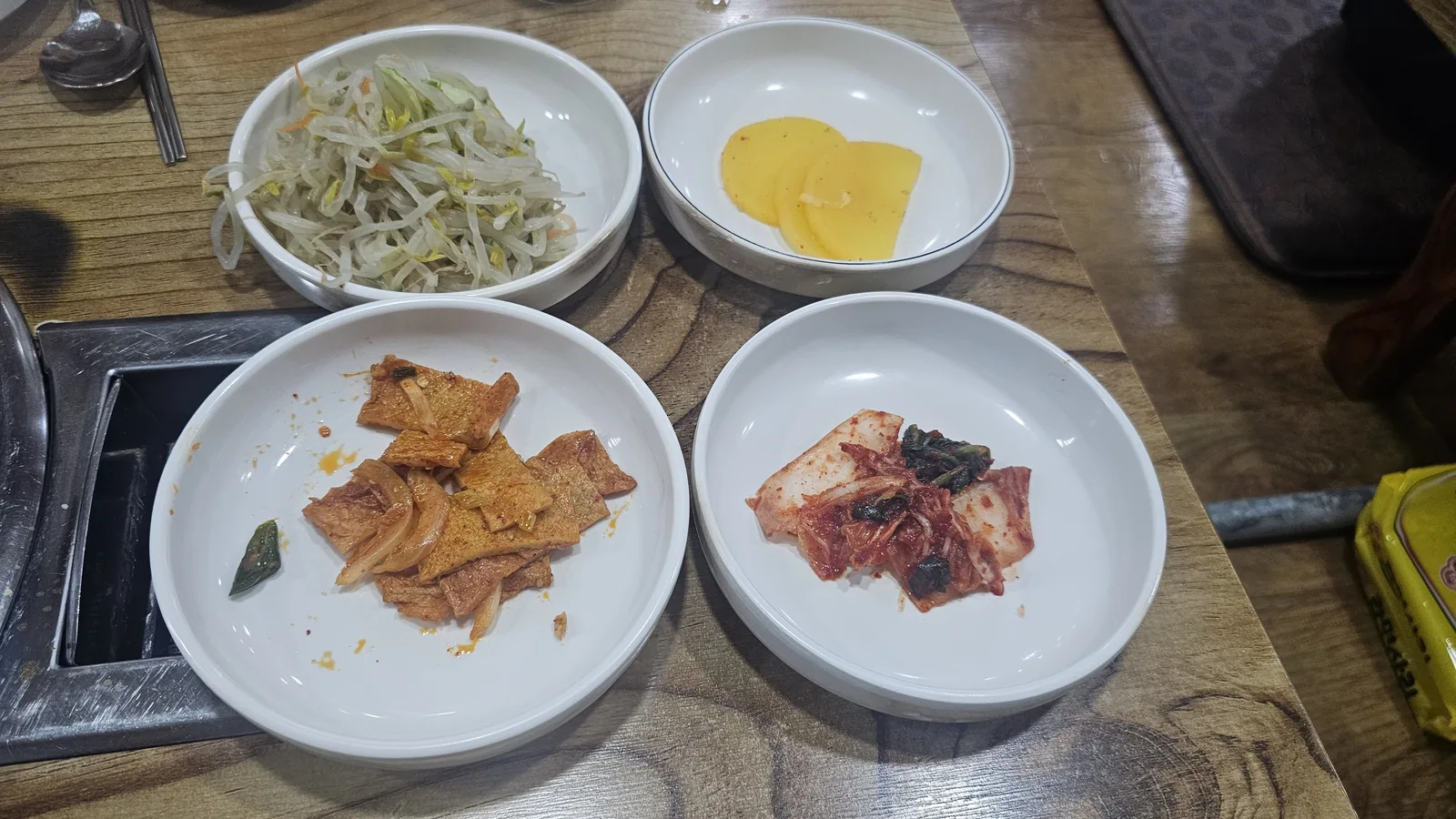 もやしの和え物、大根の漬物、豚肉の辛炒め、カクトゥギの4品が並ぶサムォンジョン汝矣島のバンチャン