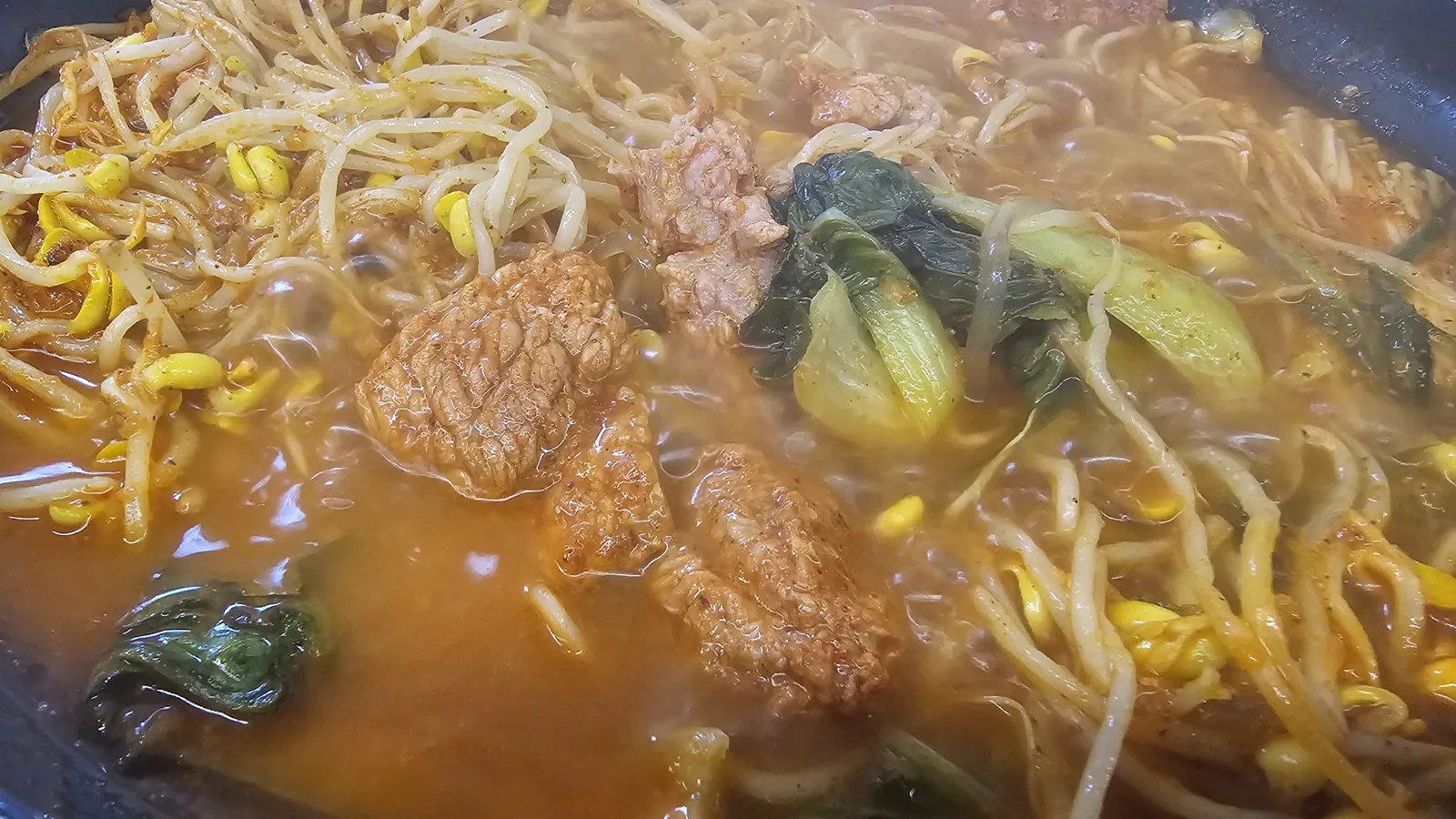 Spicy wang-galbi stew after cooking with rib meat, bean sprouts, and bok choy in rich red broth