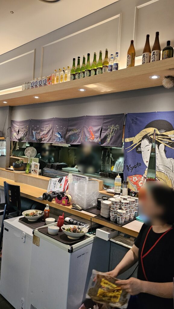 Open sushi kitchen and bar counter at Shinhee Sushi with noren curtains and sake bottles