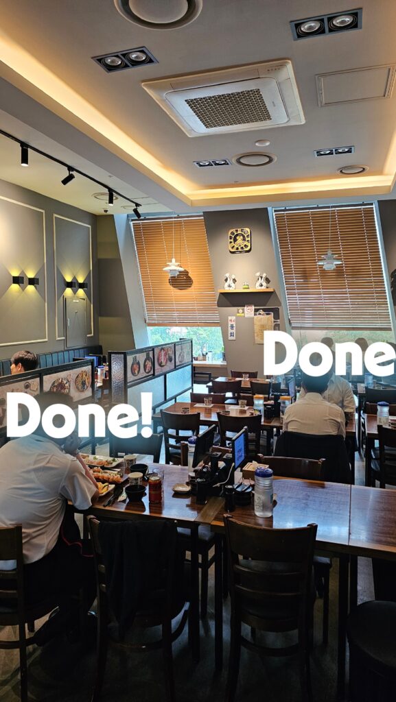 Interior of Shinhee Sushi Yeouido with wooden tables bamboo blinds and seated lunch crowd