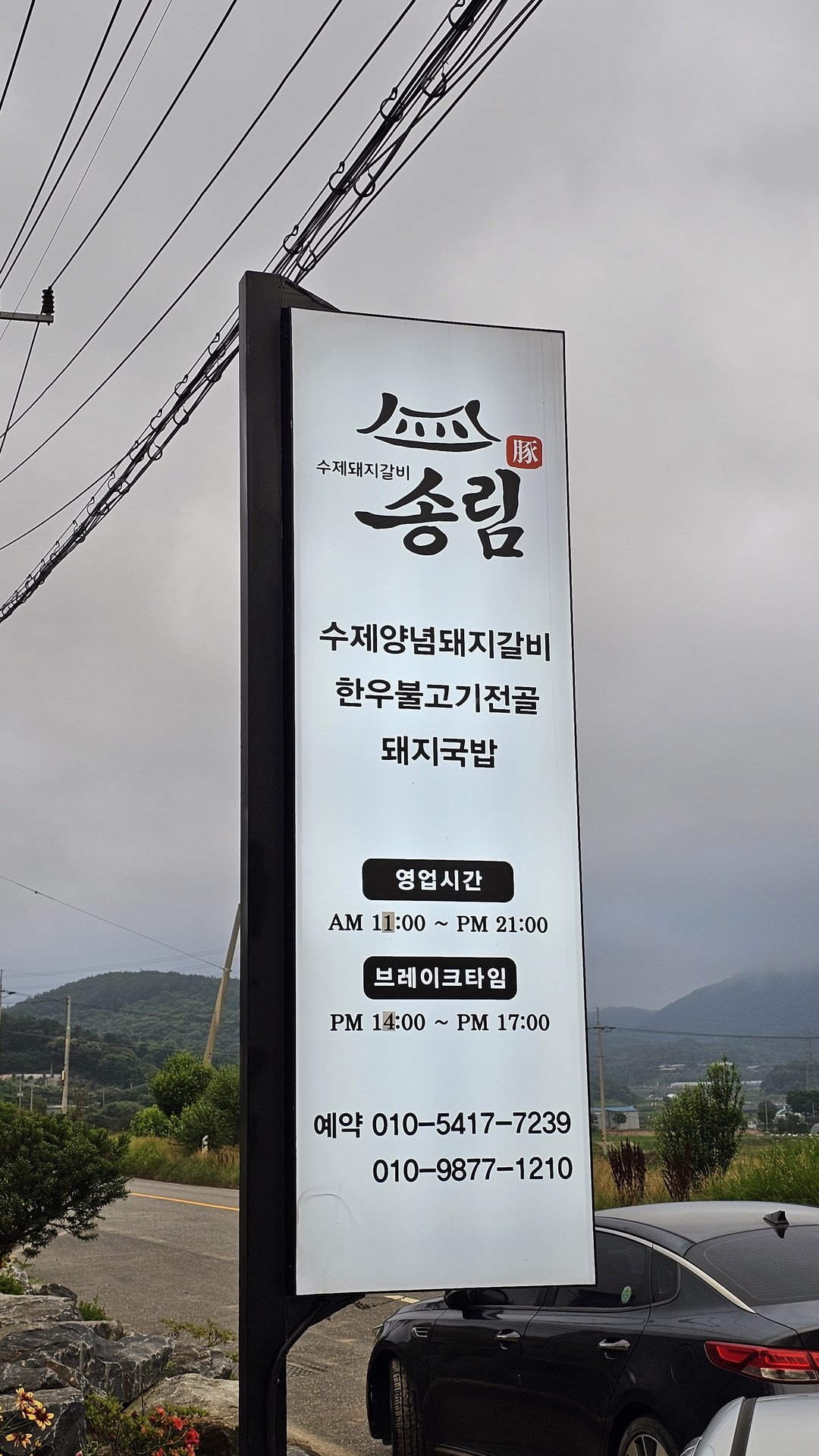Songnim signboard showing house-made marinated pork ribs, hanu bulgogi hot pot, pork gukbap, and hours 11:00–21:00