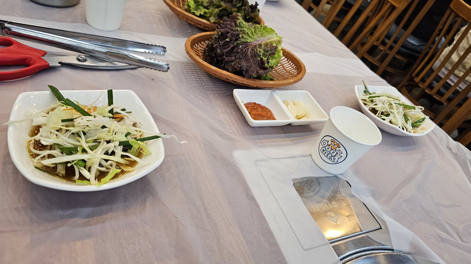 Banchan side dishes at Songnim — green onion salad, fresh lettuce, doenjang paste, bean sprout namul, tongs and scissors