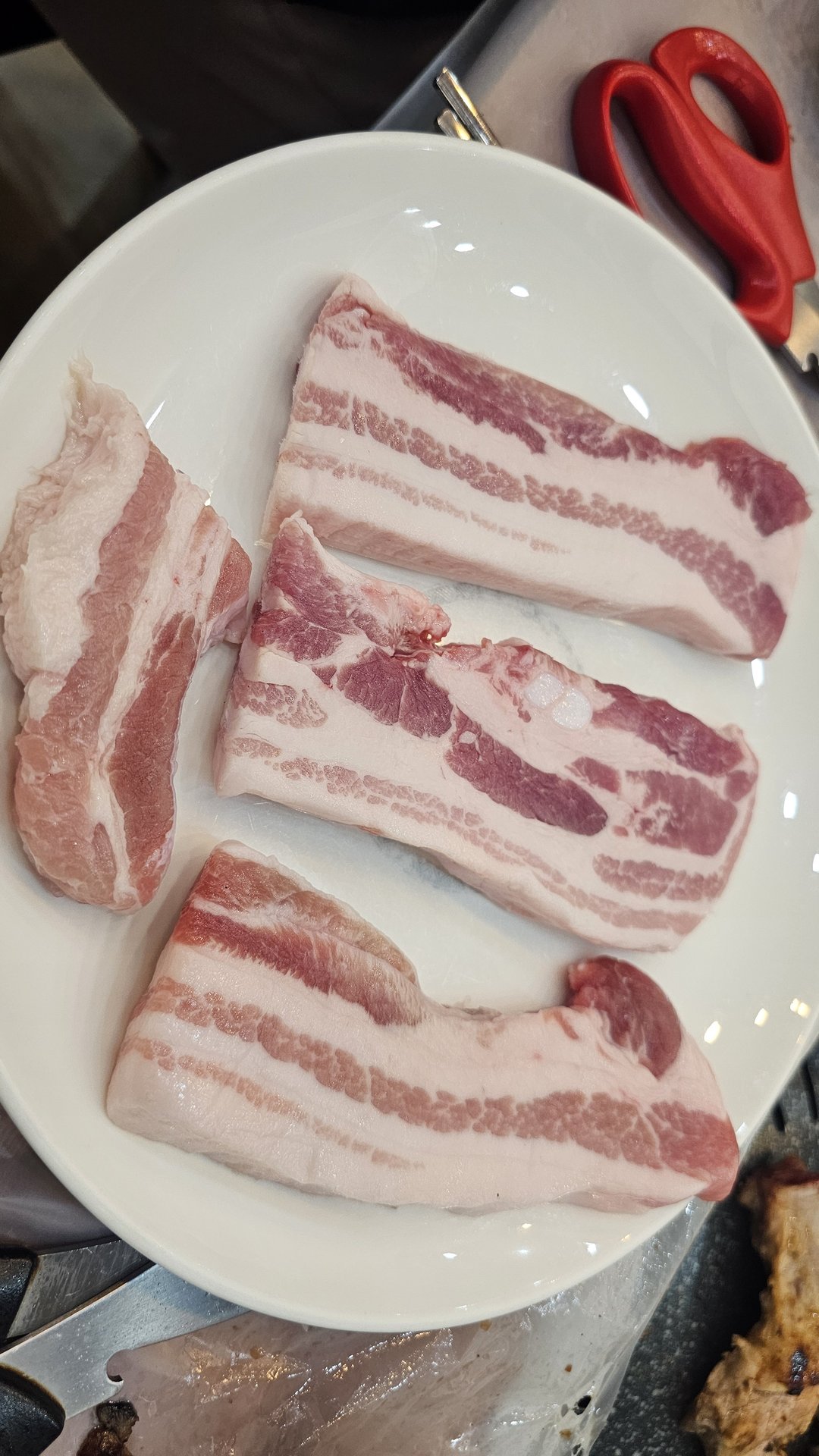 Raw thick-cut pork belly (saeng-samgyeopsal) on a plate before grilling at Songnim Cheongyang