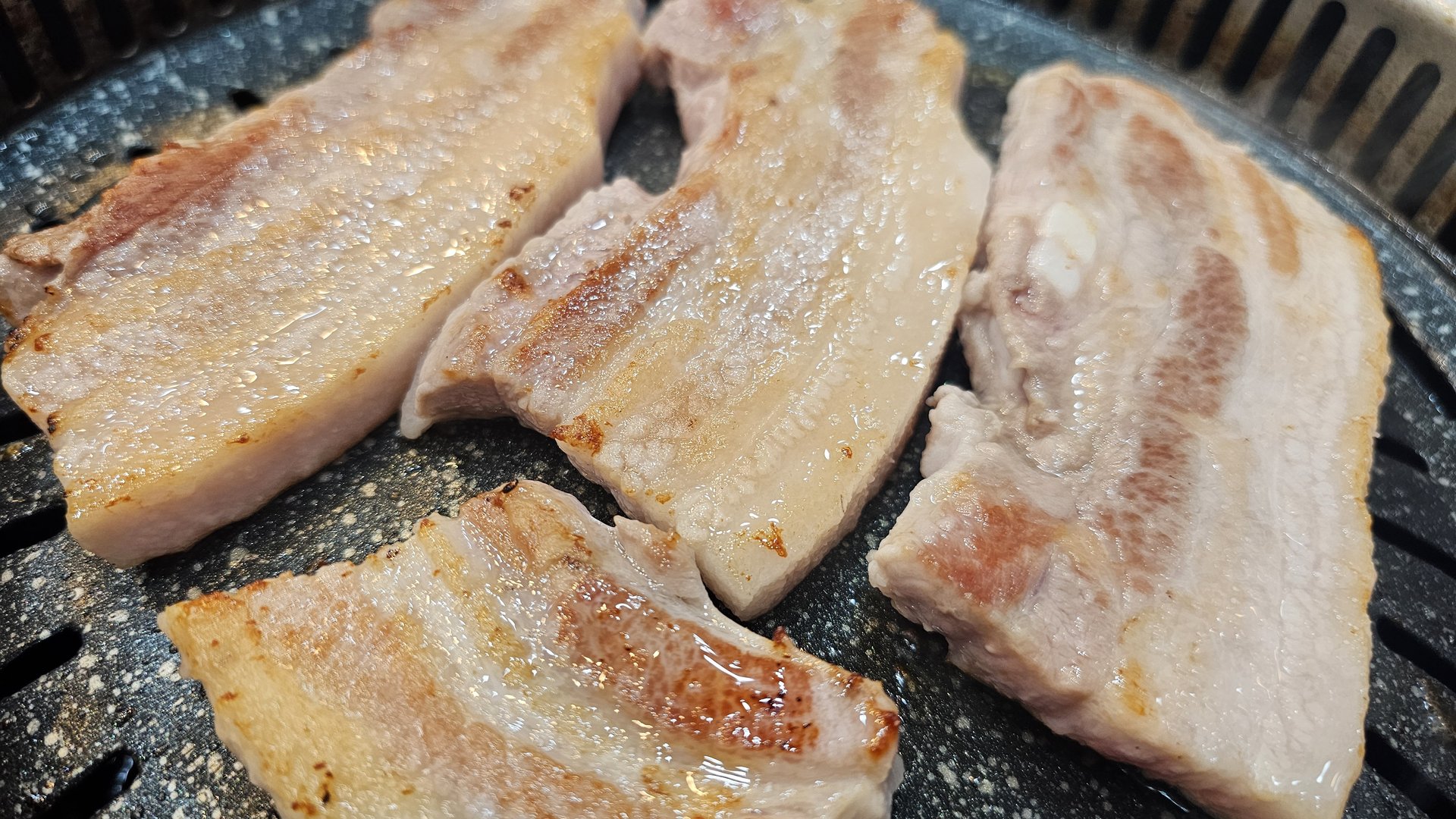 Pork belly mid-grill with fat rendering and browning at Songnim Cheongyang