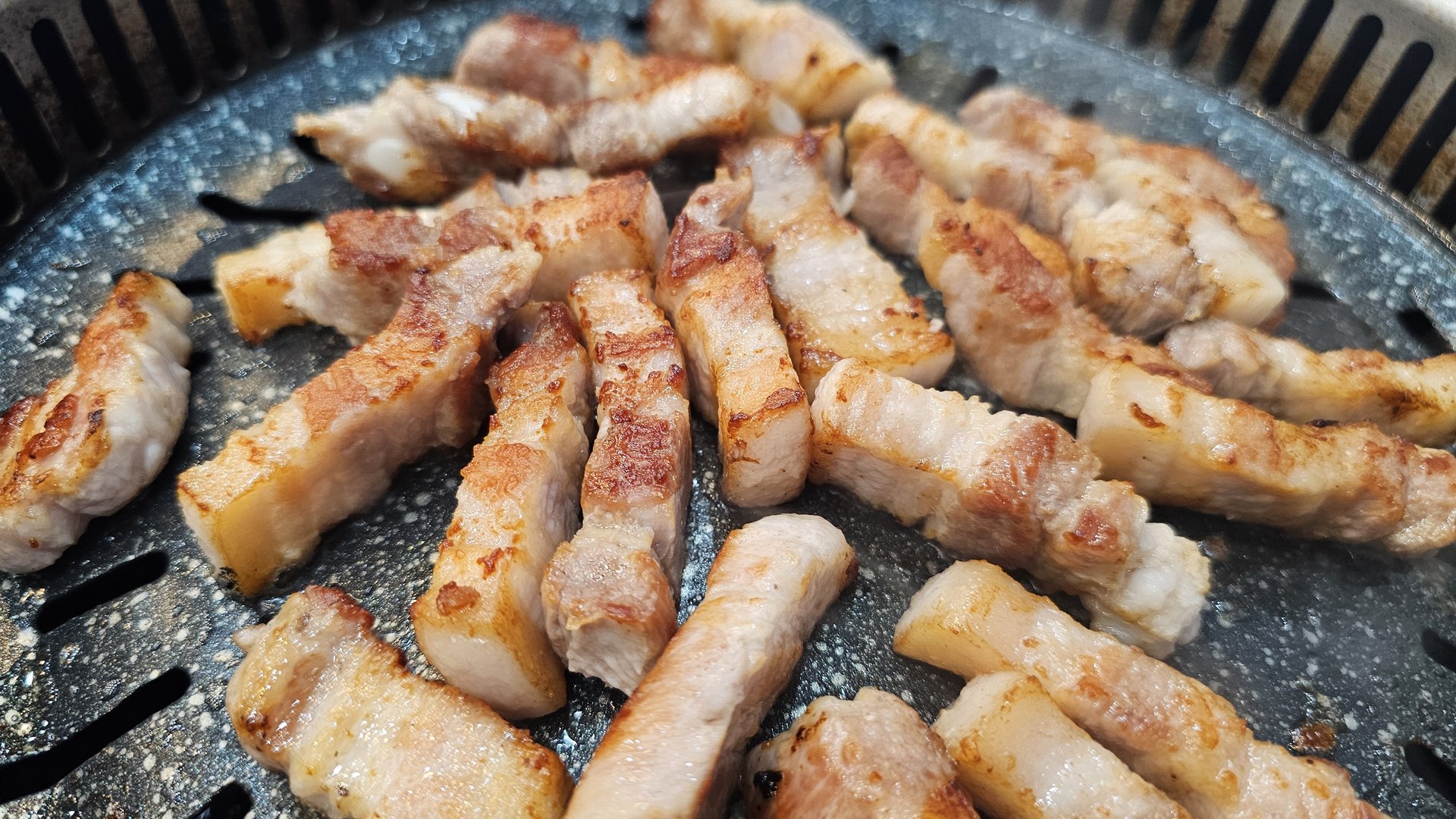 Fully cooked and sliced pork belly, golden-brown on the grill at Songnim