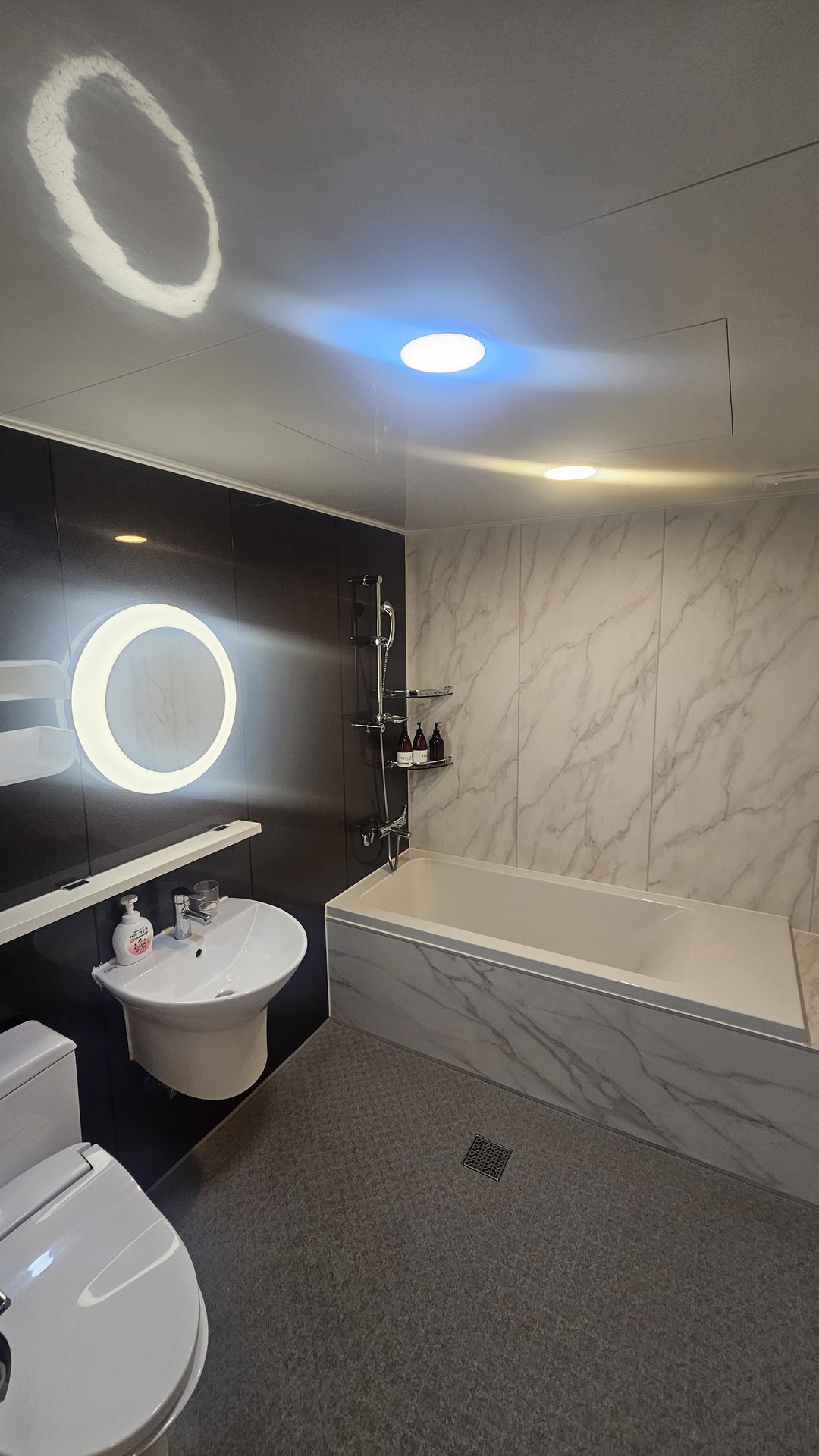 Bathroom at Vivace Resort Hadong with marble-pattern tile walls, black floor, sink and toilet