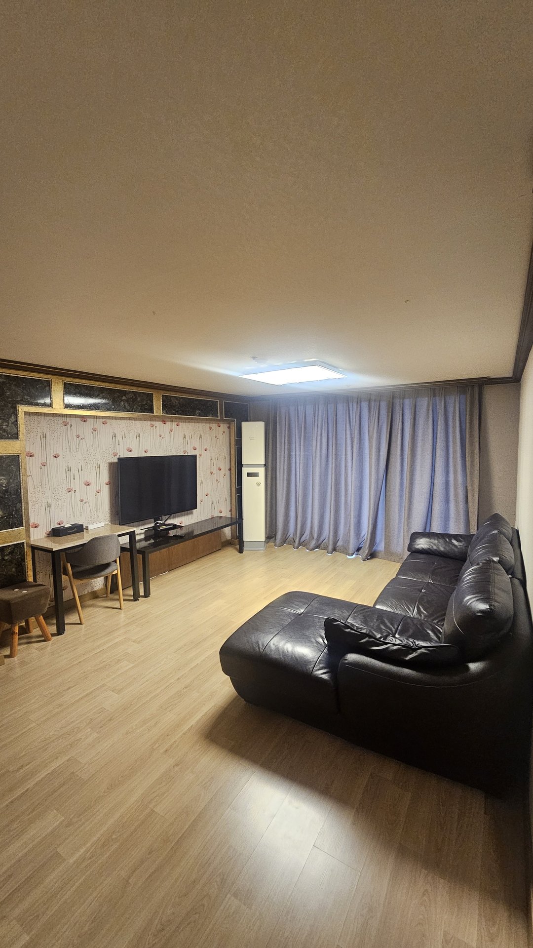 Living room in Vivace Resort Royal Suite with black leather sofa, carpet, TV and blue curtains