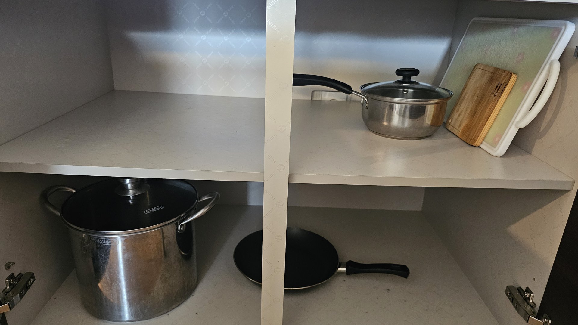 Kitchen storage cabinet with large pot, saucepan, frying pan and cutting board at Vivace Resort