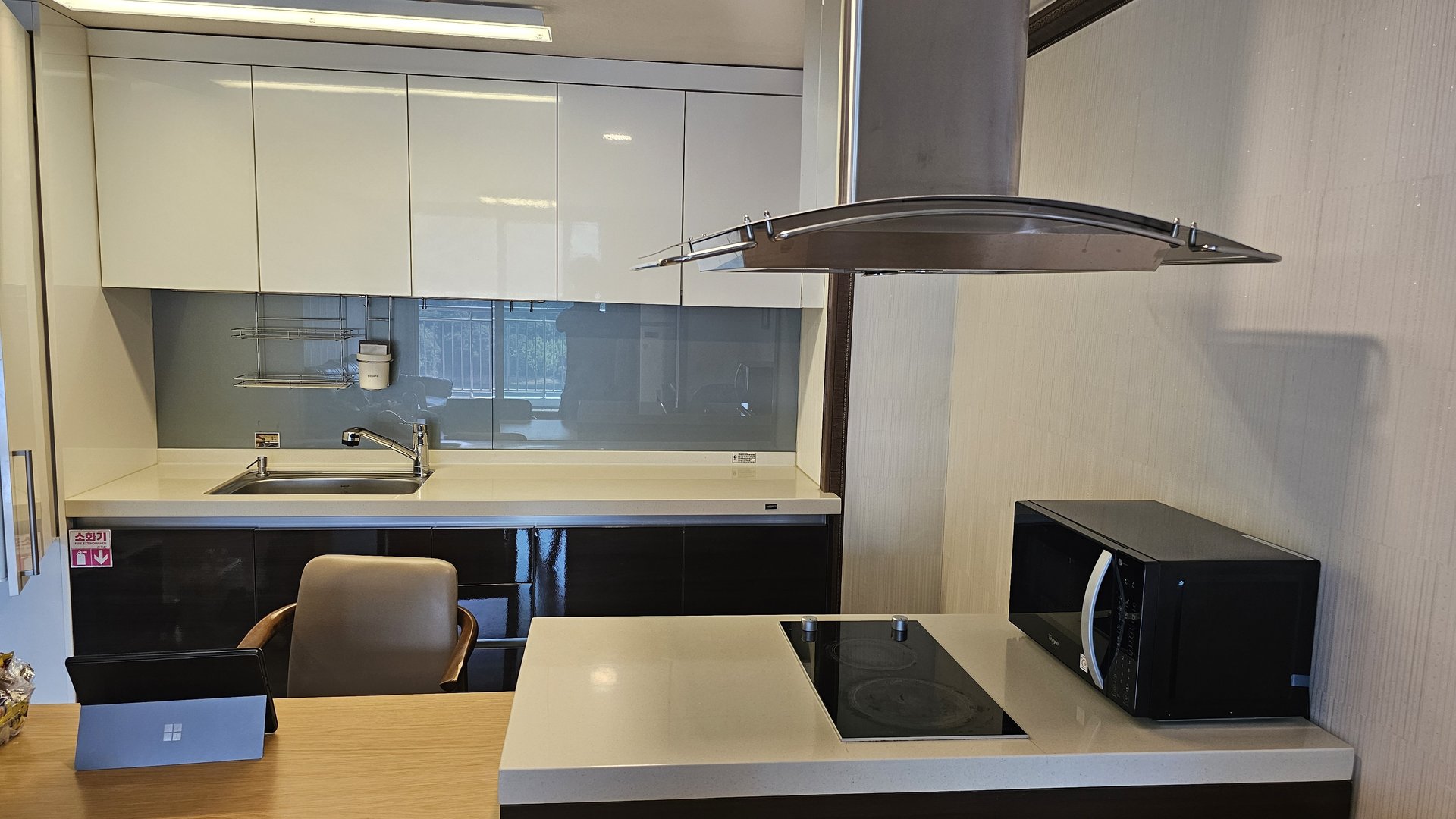 Full kitchen view of Vivace Resort Royal Suite showing induction cooktop, hood, microwave and dining table