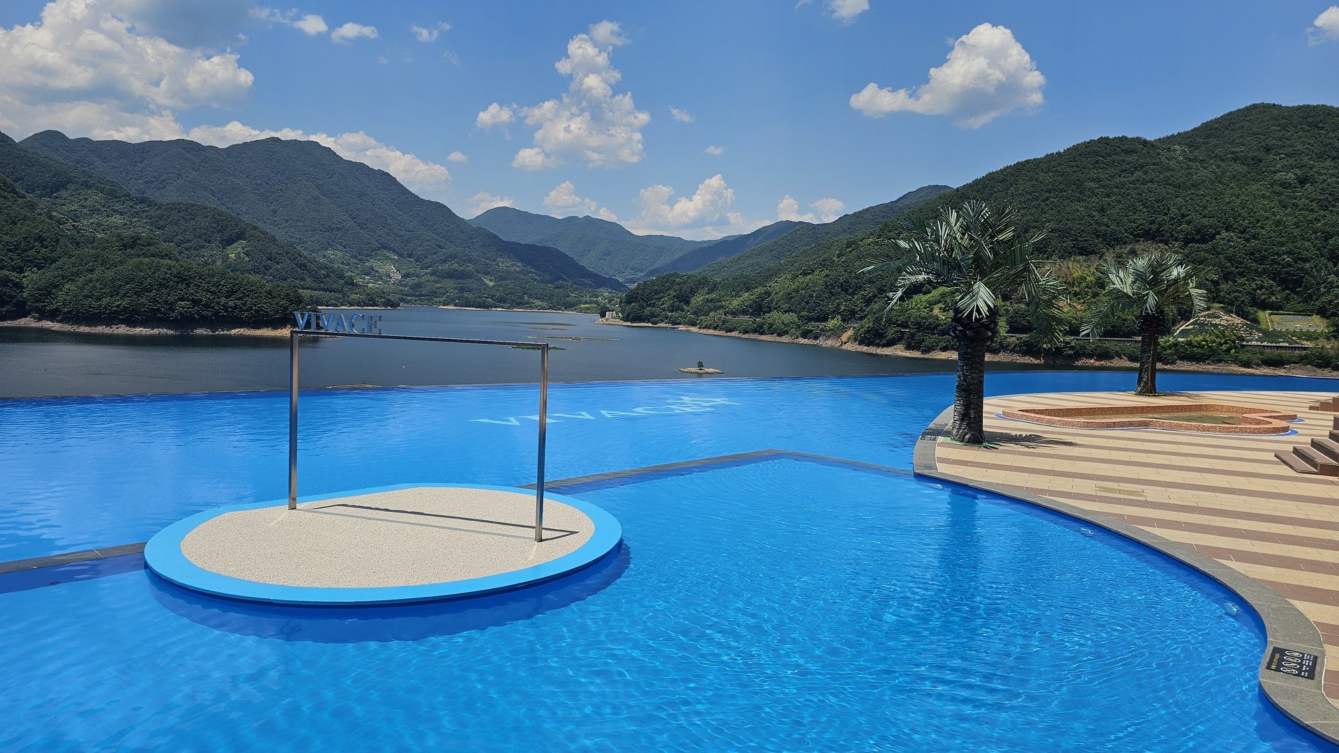 Vivace Resort infinity pool full view with VIVACE sign sculpture, river and mountain panorama