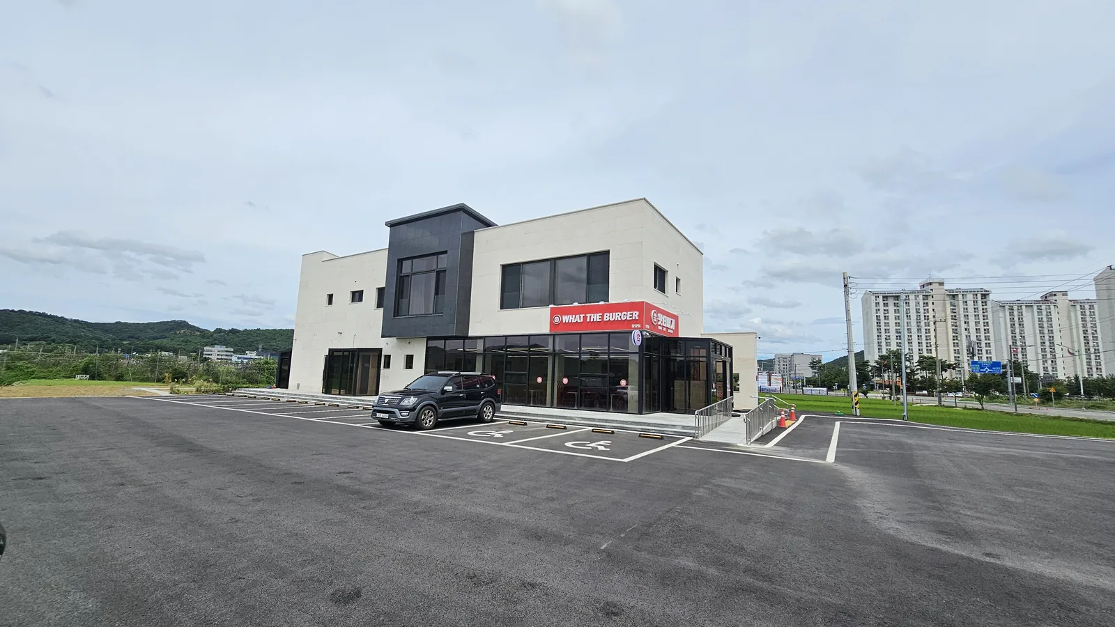ワット・ザ・バーガー청양店の外観 — 赤い看板が目立つ白黒2階建ての建物と広い駐車場