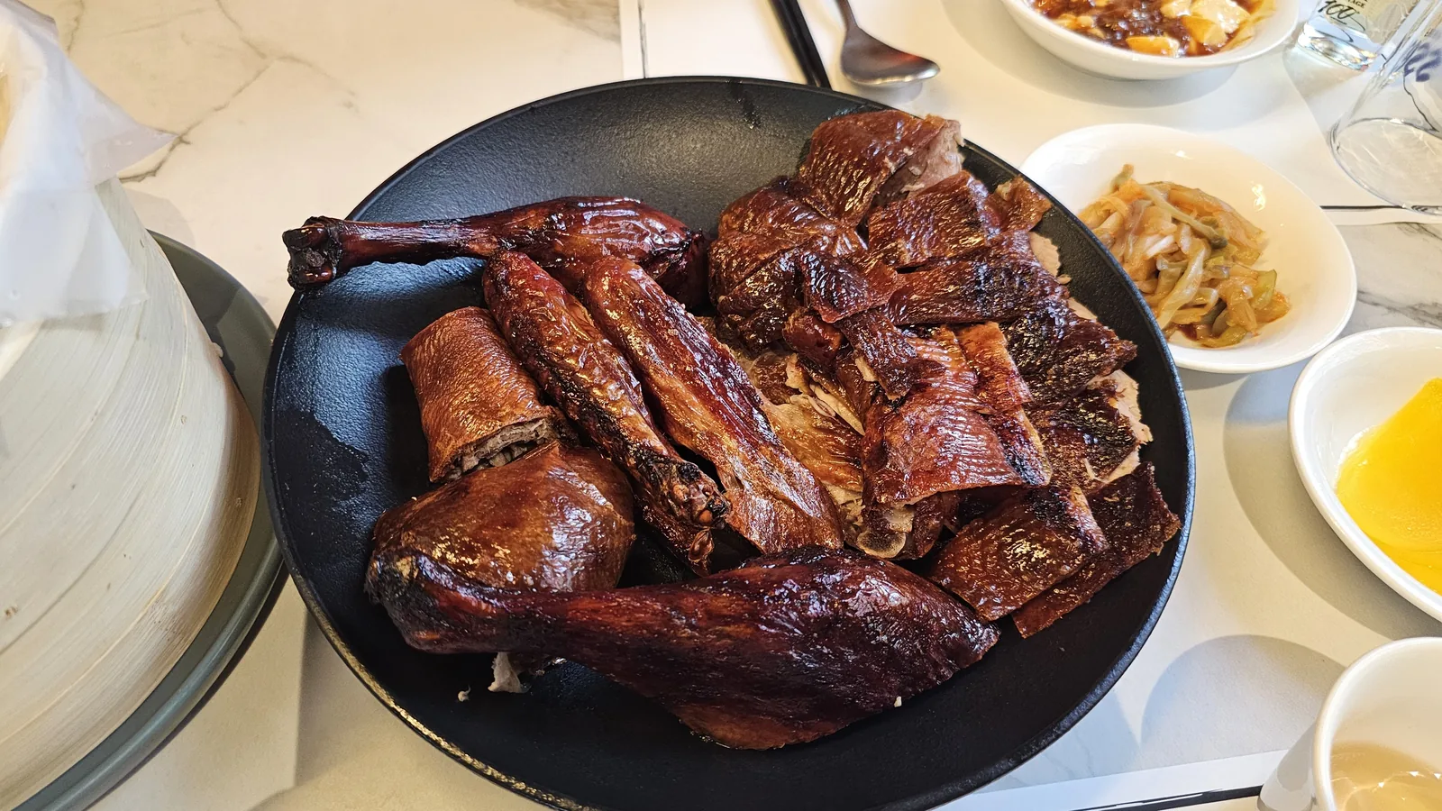 Carved Peking duck portions arranged on black round plate at Xin Hong Lou Yeouido