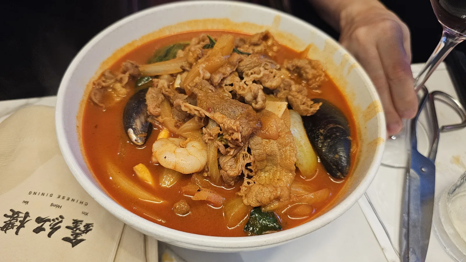 Spicy seafood jjamppong in Xin Hong Lou branded bowl with mussels shrimp and pork
